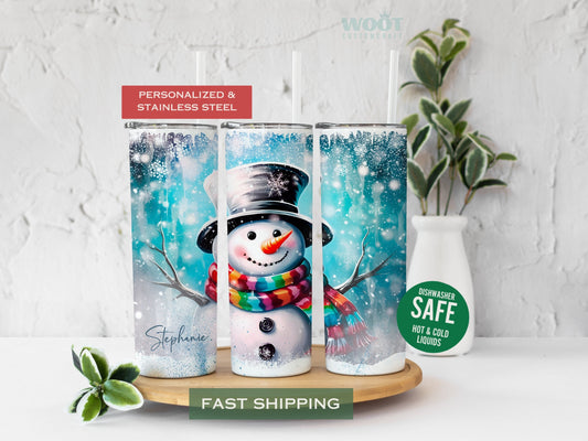 Three tumblers are showing all sides of a Christmas Winter Tumbler. A snowy scene with a blue background. A Snowman in the center, some Christmas trees, and a personalized name on the button of the tumbler.
